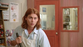 Movie still from “What's Eating Gilbert Grape” (1993), directed by Lasse Hallström – A man with long red hair holding a knife; Medium shot, Low angle