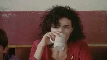 Movie still from “What's Eating Gilbert Grape” (1993), directed by Lasse Hallström – A woman drinking from a white mug while sitting in a booth; Close Up shot, Over the shoulder angle