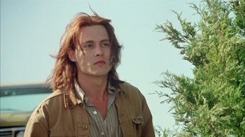 Movie still from “What's Eating Gilbert Grape” (1993), directed by Lasse Hallström – A man with long red hair standing next to a tree; Close Up shot, Low angle