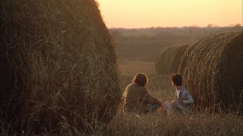 Movie still from “What's Eating Gilbert Grape” (1993), directed by Lasse Hallström – Two people sitting in a field near hay bales; Wide shot, Over the shoulder angle
