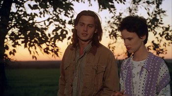 Movie still from “What's Eating Gilbert Grape” (1993), directed by Lasse Hallström – A man and a woman standing next to each other under a tree; Medium shot, Over the shoulder angle