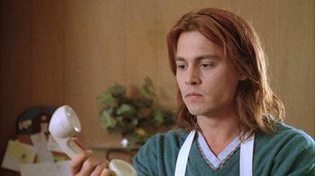 Movie still from “What's Eating Gilbert Grape” (1993), directed by Lasse Hallström – A man with long red hair is holding something; Close Up shot, Low angle