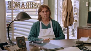 Movie still from “What's Eating Gilbert Grape” (1993), directed by Lasse Hallström – A man sitting at a table in front of a window; Medium shot, Low angle