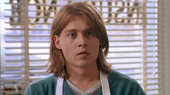 Movie still from “What's Eating Gilbert Grape” (1993), directed by Lasse Hallström – A man with long brown hair wearing an apron; Close Up shot, Low angle