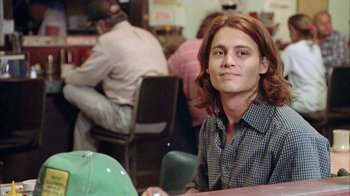 Movie still from “What's Eating Gilbert Grape” (1993), directed by Lasse Hallström – A man sitting at a table in front of a group of people; Close Up shot, Low angle