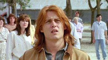 Movie still from “What's Eating Gilbert Grape” (1993), directed by Lasse Hallström – A man with long red hair is looking at the camera; Close Up shot, Low angle