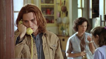 Movie still from “What's Eating Gilbert Grape” (1993), directed by Lasse Hallström – A man with long red hair is holding a phone; Close Up shot, High angle