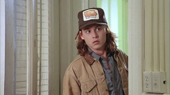 Movie still from “What's Eating Gilbert Grape” (1993), directed by Lasse Hallström – A man with long hair wearing a brown hat; Close Up shot, Over the shoulder angle