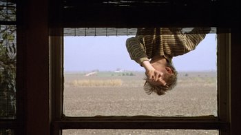 Movie still from “What's Eating Gilbert Grape” (1993), directed by Lasse Hallström – A man hanging upside down in a field; Medium shot, Low angle