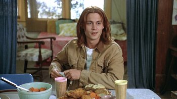 Movie still from “What's Eating Gilbert Grape” (1993), directed by Lasse Hallström – A man sitting at a table with food in front of him; Medium shot, High angle