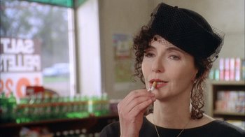 Movie still from “What's Eating Gilbert Grape” (1993), directed by Lasse Hallström – A woman in a black hat is smoking a cigarette; Close Up shot, Over the shoulder angle