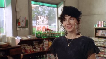 Movie still from “What's Eating Gilbert Grape” (1993), directed by Lasse Hallström – A woman wearing a hat standing in front of a store window; Medium shot, Over the shoulder angle