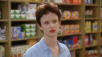 Movie still from “What's Eating Gilbert Grape” (1993), directed by Lasse Hallström – A young woman in a blue shirt is in a store; Close Up shot, Over the shoulder angle