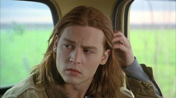 Movie still from “What's Eating Gilbert Grape” (1993), directed by Lasse Hallström – A man with long brown hair is sitting in a car; Close Up shot, Low angle