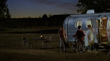 Movie still from “What's Eating Gilbert Grape” (1993), directed by Lasse Hallström – Two people standing in front of an rv at night; Wide shot, High angle