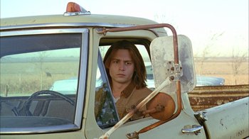 Movie still from “What's Eating Gilbert Grape” (1993), directed by Lasse Hallström – A man sitting in the driver's seat of a truck; Medium shot, Low angle