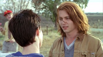 Movie still from “What's Eating Gilbert Grape” (1993), directed by Lasse Hallström – Two young men are talking outside in a field; Close Up shot, Over the shoulder angle