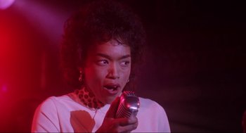 Movie still from “What's Love Got to Do with It” (1993), directed by Brian Gibson – A woman holding a microphone in her hand; Close Up shot, Low angle