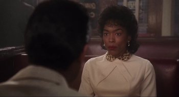 Movie still from “What's Love Got to Do with It” (1993), directed by Brian Gibson – A woman in a white dress is looking at a man in a black suit; Close Up shot, Over the shoulder angle