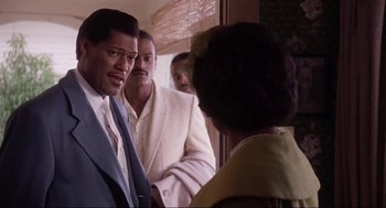 Movie still from “What's Love Got to Do with It” (1993), directed by Brian Gibson – A group of men standing next to each other in front of a woman; Close Up shot, Over the shoulder angle