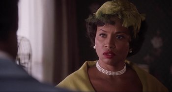 Movie still from “What's Love Got to Do with It” (1993), directed by Brian Gibson – A woman wearing a hat and a yellow dress; Close Up shot, Over the shoulder angle
