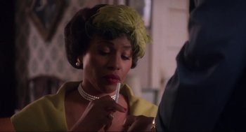 Movie still from “What's Love Got to Do with It” (1993), directed by Brian Gibson – A woman in a yellow dress holding a pen; Close Up shot, Over the shoulder angle