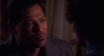 Movie still from “What's Love Got to Do with It” (1993), directed by Brian Gibson – A person wearing a suit and tie; Close Up shot, Over the shoulder angle