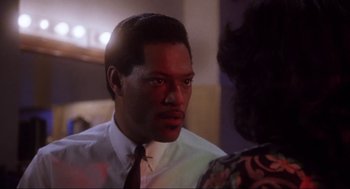 Movie still from “What's Love Got to Do with It” (1993), directed by Brian Gibson – A man wearing a white shirt and a red tie; Close Up shot, Over the shoulder angle