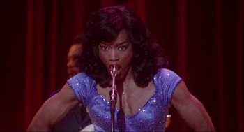 Movie still from “What's Love Got to Do with It” (1993), directed by Brian Gibson – A woman that is holding a microphone in her mouth; Close Up shot, Low angle