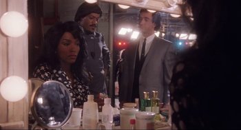 Movie still from “What's Love Got to Do with It” (1993), directed by Brian Gibson – A group of people standing in front of a bathroom mirror; Medium shot, Over the shoulder angle