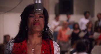 Movie still from “What's Love Got to Do with It” (1993), directed by Brian Gibson – A woman is standing in front of a microphone; Close Up shot, Low angle