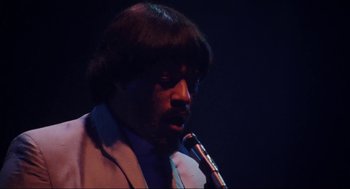 Movie still from “What's Love Got to Do with It” (1993), directed by Brian Gibson – A man in a suit and tie holding a pipe in his mouth; Close Up shot, Low angle