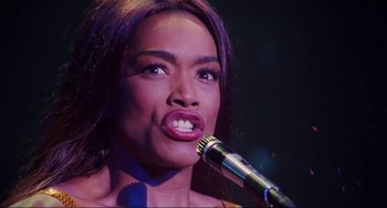 Movie still from “What's Love Got to Do with It” (1993), directed by Brian Gibson – A woman that is holding a microphone up to her mouth; Close Up shot, Low angle
