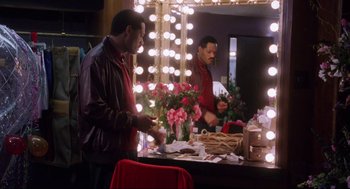 Movie still from “What's Love Got to Do with It” (1993), directed by Brian Gibson – A man standing in front of a mirror in a dressing room; Medium shot, Over the shoulder angle