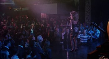 Movie still from “What's Love Got to Do with It” (1993), directed by Brian Gibson – A crowd of people sitting and standing in a room; Wide shot, High angle