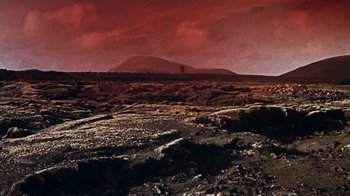 Movie still from “When Dinosaurs Ruled the Earth” (1970), directed by Val Guest – A red sky over a barren landscape with a tree in the distance; Extreme Wide shot, High angle