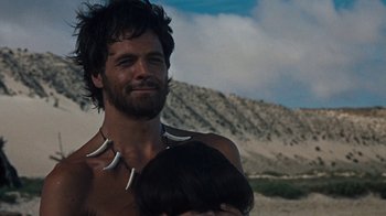 Movie still from “When Dinosaurs Ruled the Earth” (1970), directed by Val Guest – A man with long hair and a beard is holding a child; Close Up shot, Low angle