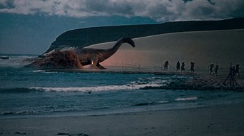 Movie still from “When Dinosaurs Ruled the Earth” (1970), directed by Val Guest – A large dinosaur on a beach with people walking around; Extreme Wide shot, Low angle