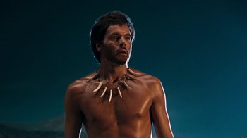 Movie still from “When Dinosaurs Ruled the Earth” (1970), directed by Val Guest – A shirtless man with a necklace on his neck; Close Up shot, Low angle
