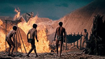 Movie still from “When Dinosaurs Ruled the Earth” (1970), directed by Val Guest – Two young boys are walking in front of a fire; Wide shot, Low angle