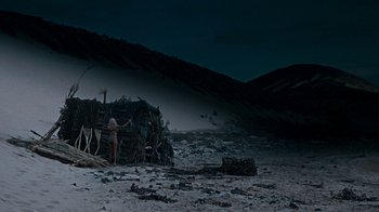 Movie still from “When Dinosaurs Ruled the Earth” (1970), directed by Val Guest – A woman standing in front of a pile of debris on the beach; Extreme Wide shot, Low angle