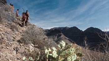 Movie still from “When Dinosaurs Ruled the Earth” (1970), directed by Val Guest – Two people on a hill with a cactus in the background; Extreme Wide shot, Low angle