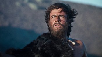 Movie still from “When Dinosaurs Ruled the Earth” (1970), directed by Val Guest – A man with long hair and a beard is looking up; Close Up shot, Low angle