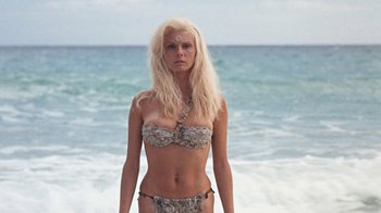 Movie still from “When Dinosaurs Ruled the Earth” (1970), directed by Val Guest – A woman standing on the beach wearing a bikini; Medium shot, Low angle