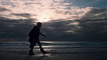 Movie still from “When Dinosaurs Ruled the Earth” (1970), directed by Val Guest – A person walking on the beach with a skateboard; Extreme Wide shot, Low angle