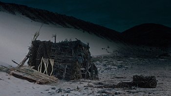 Movie still from “When Dinosaurs Ruled the Earth” (1970), directed by Val Guest – A pile of wood sitting on top of a sandy beach; Extreme Wide shot, High angle