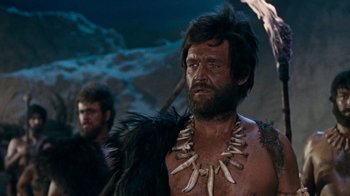 Movie still from “When Dinosaurs Ruled the Earth” (1970), directed by Val Guest – A person wearing a necklace; Medium shot, Low angle