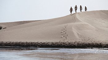 Movie still from “When Dinosaurs Ruled the Earth” (1970), directed by Val Guest – A group of people walking on top of a sand dune; Extreme Wide shot, Low angle