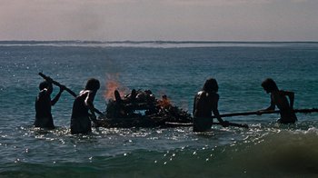 Movie still from “When Dinosaurs Ruled the Earth” (1970), directed by Val Guest – A group of people in the water near a bonfire; Extreme Wide shot, High angle