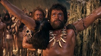 Movie still from “When Dinosaurs Ruled the Earth” (1970), directed by Val Guest – A man with a bunch of fake teeth on his neck; Medium shot, Low angle